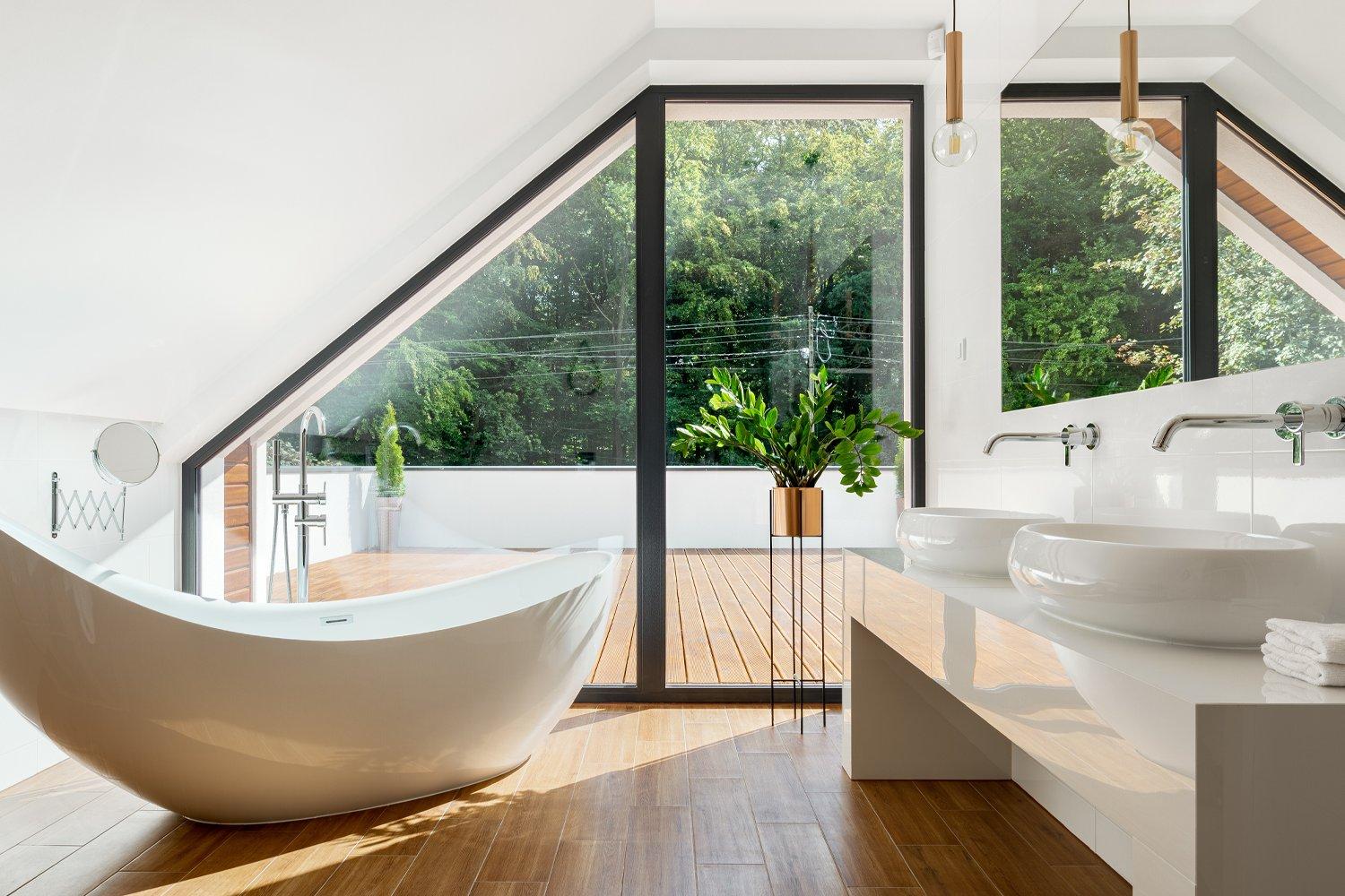 Modern bathroom with wood floors, angled window, and freestanding tub